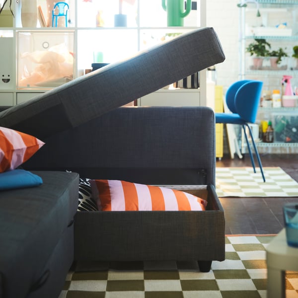 A dark grey FRIHETEN corner sofa-bed with storage, partially opened to reveal cushions inside.