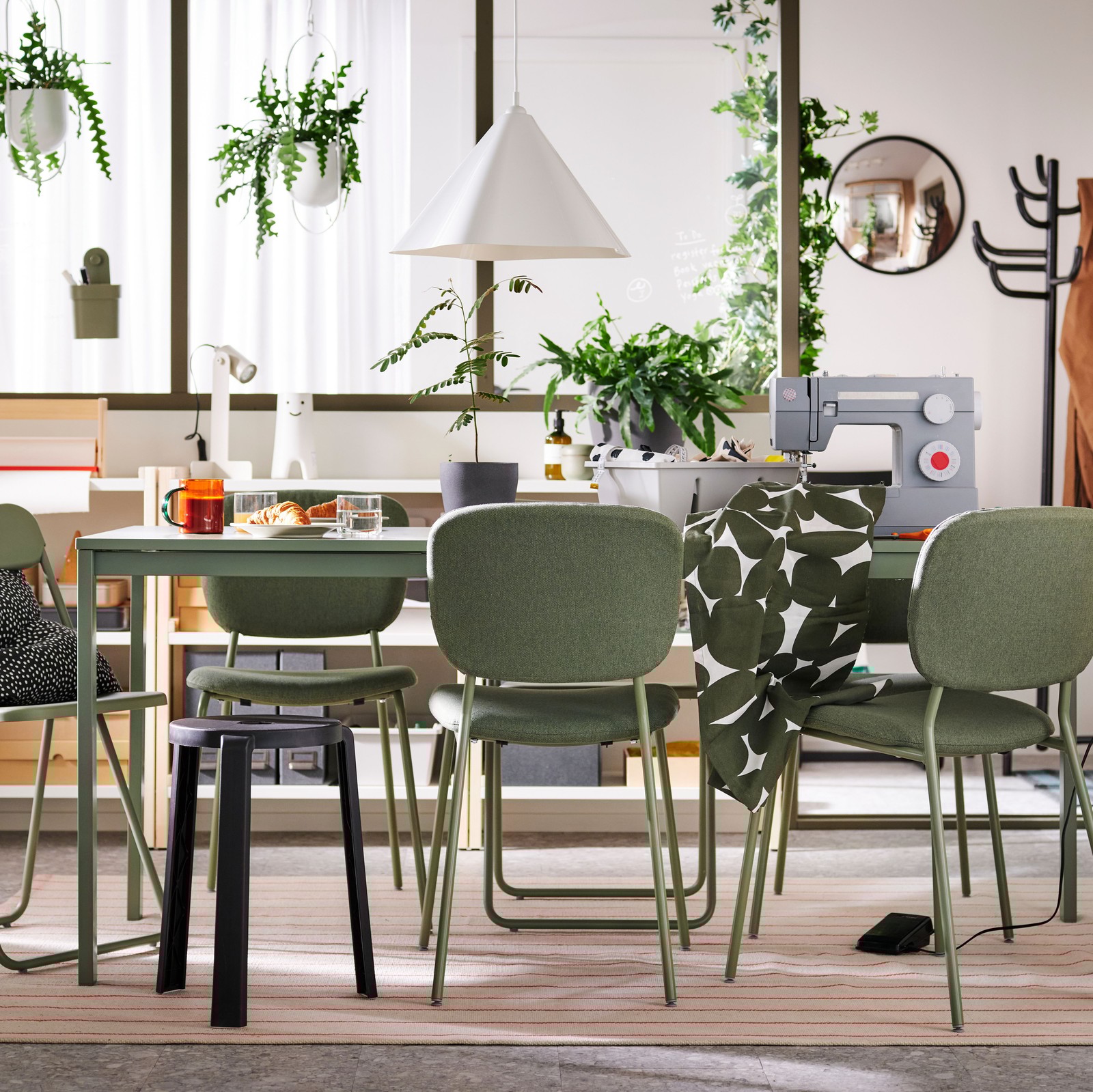 Unhas cadeiras VIHALS e un tallo a carón dunha mesa extensible VIHALS verde sobre unha alfombra nun comedor multifuncional.