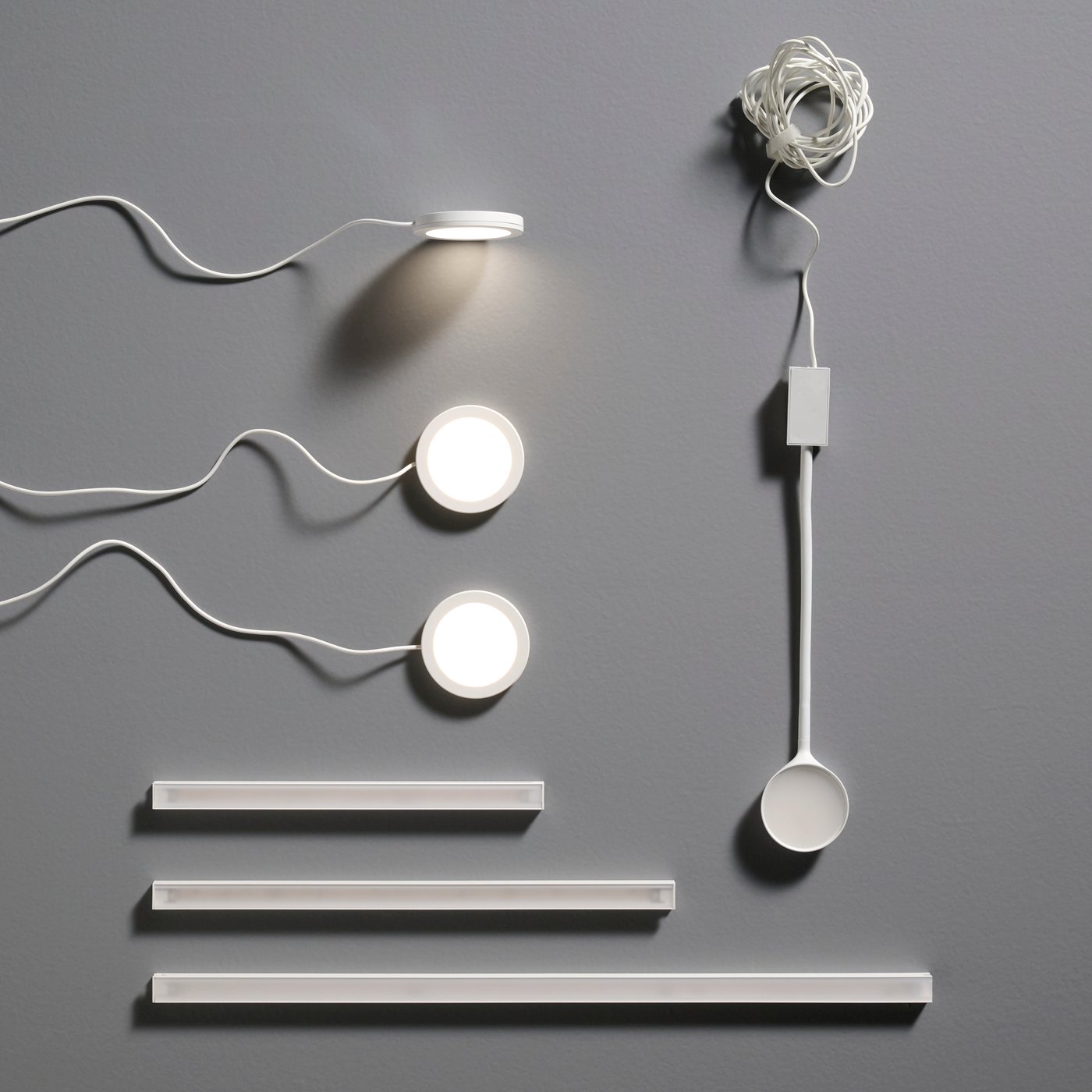 MITTLED LED-Arbeitsplattenbeleuchtung für die Küche: Lichtstreifen mit runden LED-Spots, Kabeln und verschiedenen Streifenlängen ordentlich auf einer flachen Oberfläche angeordnet.