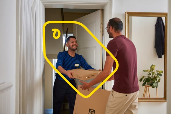 Et IKEA bud leverer en pakke hil en kunde, der tager imod pakken i døren.
