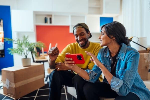 Dos personas sentados en un sofa mirando el movil, decidiendo que comprar. 