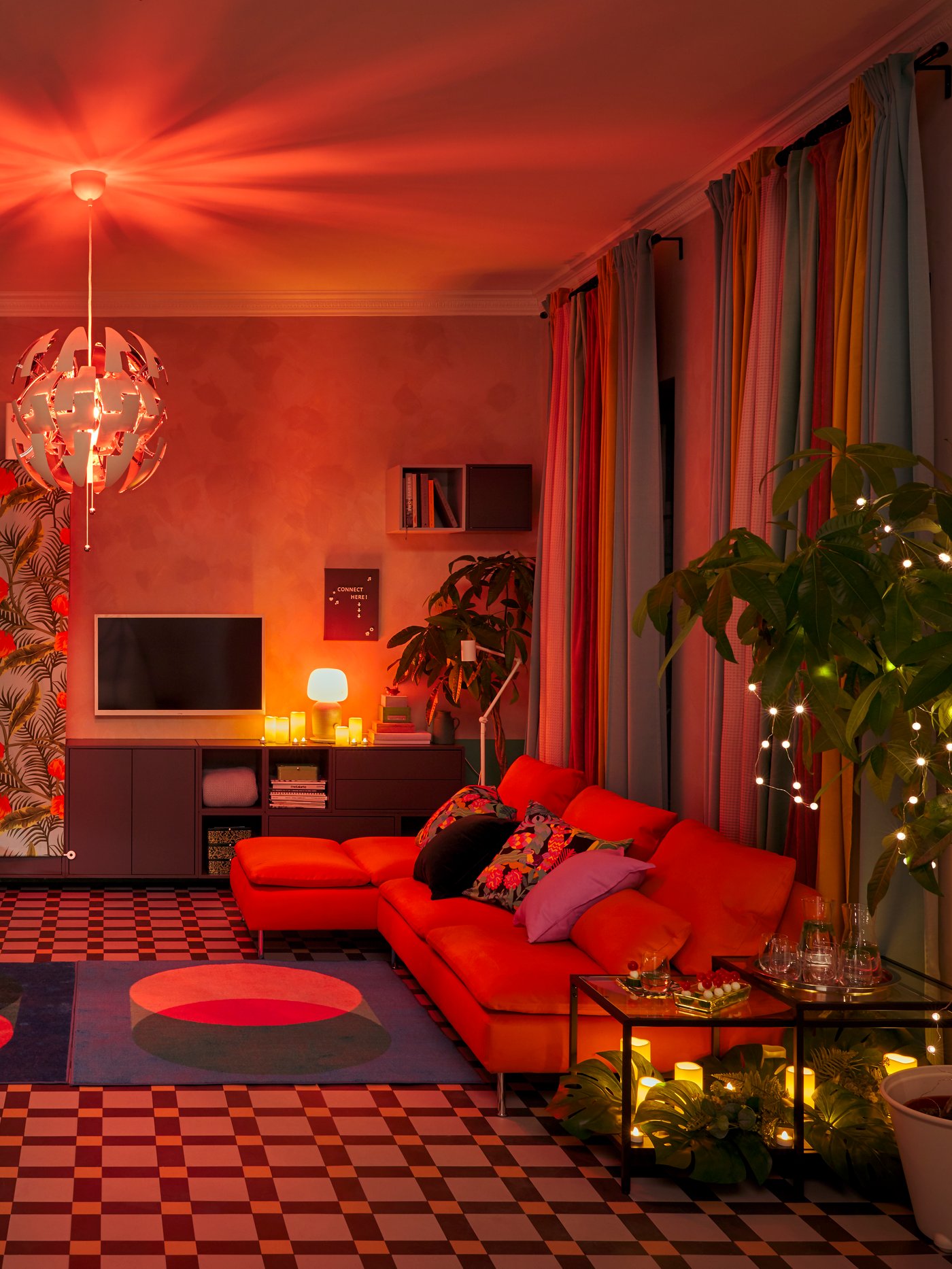 Living room with curtains, rug, four-seat sofa, cushions, wall cabinet, tables, pendant lamp, plant pots, water glasses.
