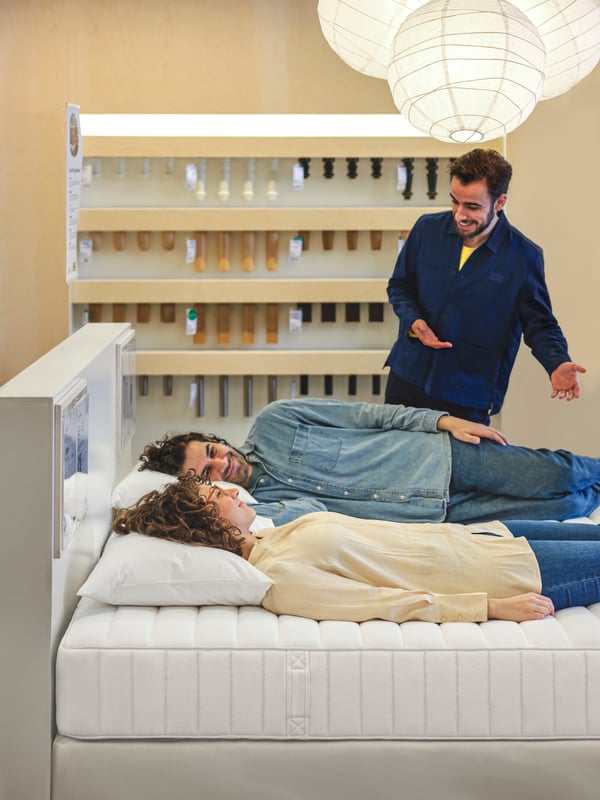 IKEA medarbejder vejleder to personer, der prøver en seng i et varehus