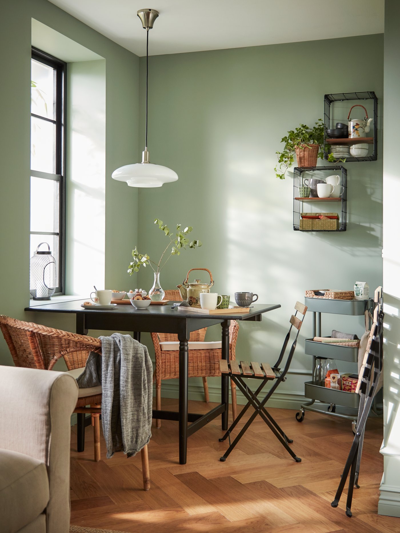 Un comedor con dos sitiales de mimbre y una silla plegable TÄRNÖ