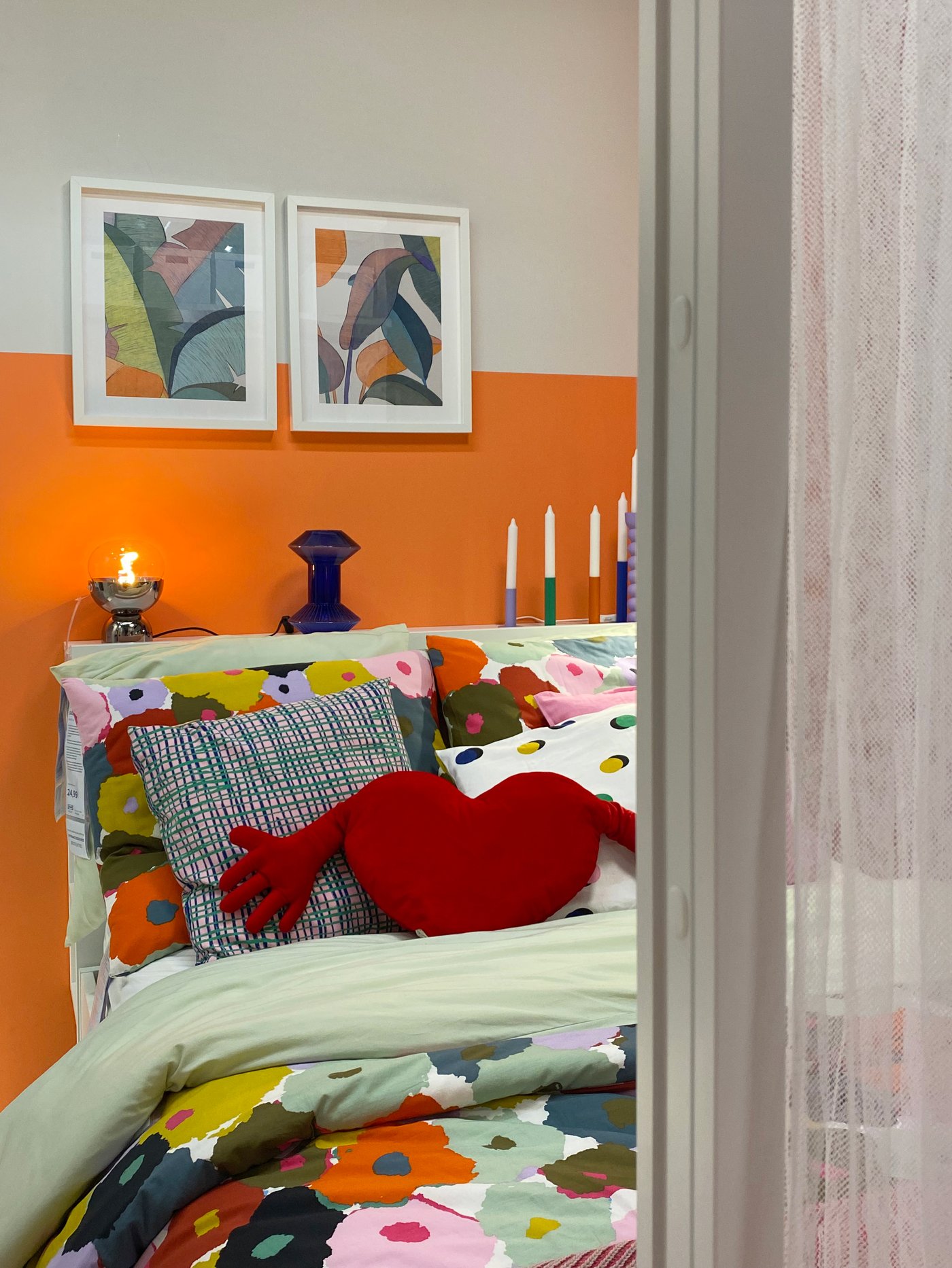 Een kleurrijke slaapkamer met gebloemd beddengoed op het bed en kaarsen op de rand