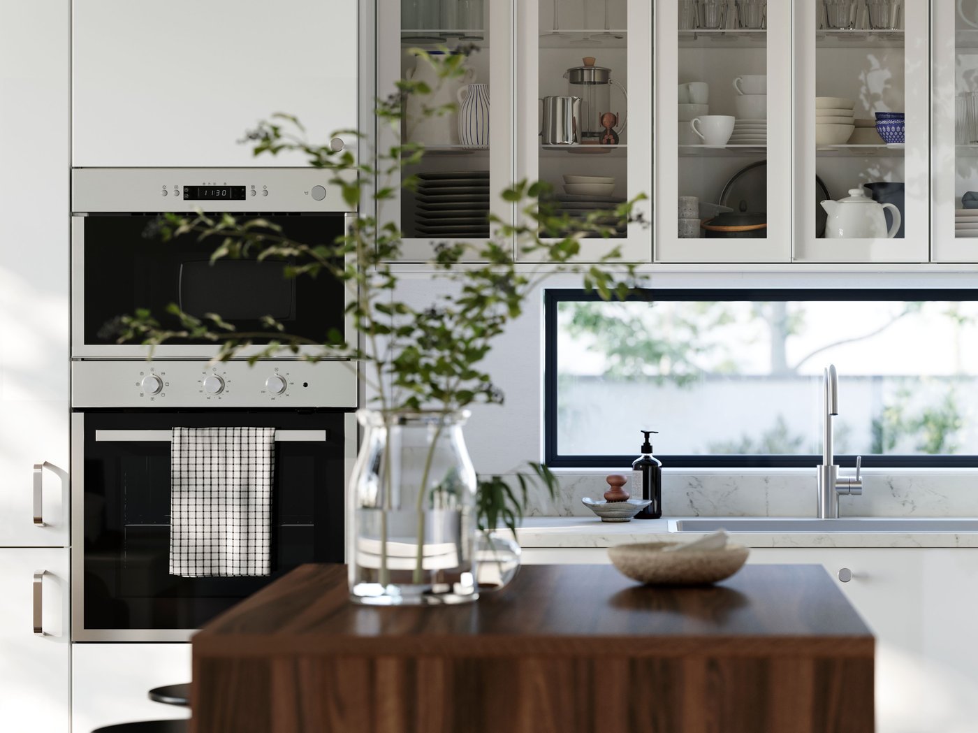 A kitchen with high-gloss RINGHULT fronts and wall cabinets with HEJSTA glass doors has a kitchen island in the foreground.
