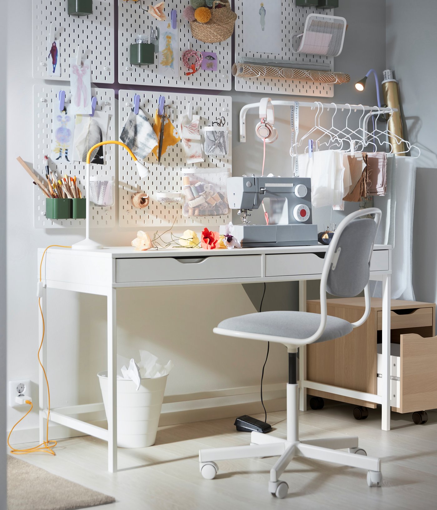 A white ALEX desk in a student room, with a drawer unit that has an opened drawer sitting next to it.