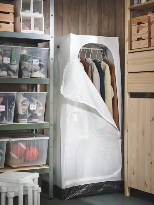 Storage area with a partially open VUKU wardrobe with clothes on hangers, next to a shelving unit with SAMLA and SKUBB boxes.