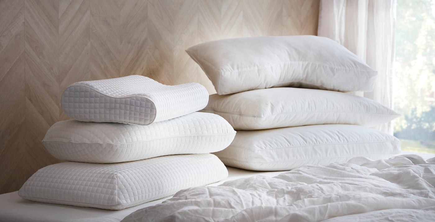 Auf einem Bett liegen 3 Pölster aufeinander gestapelt.