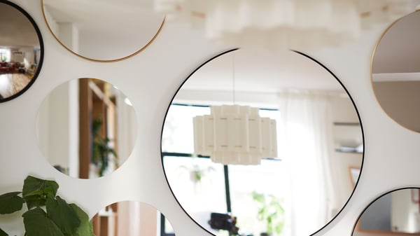 Des miroirs de différentes tailles sont accrochés à un mur.