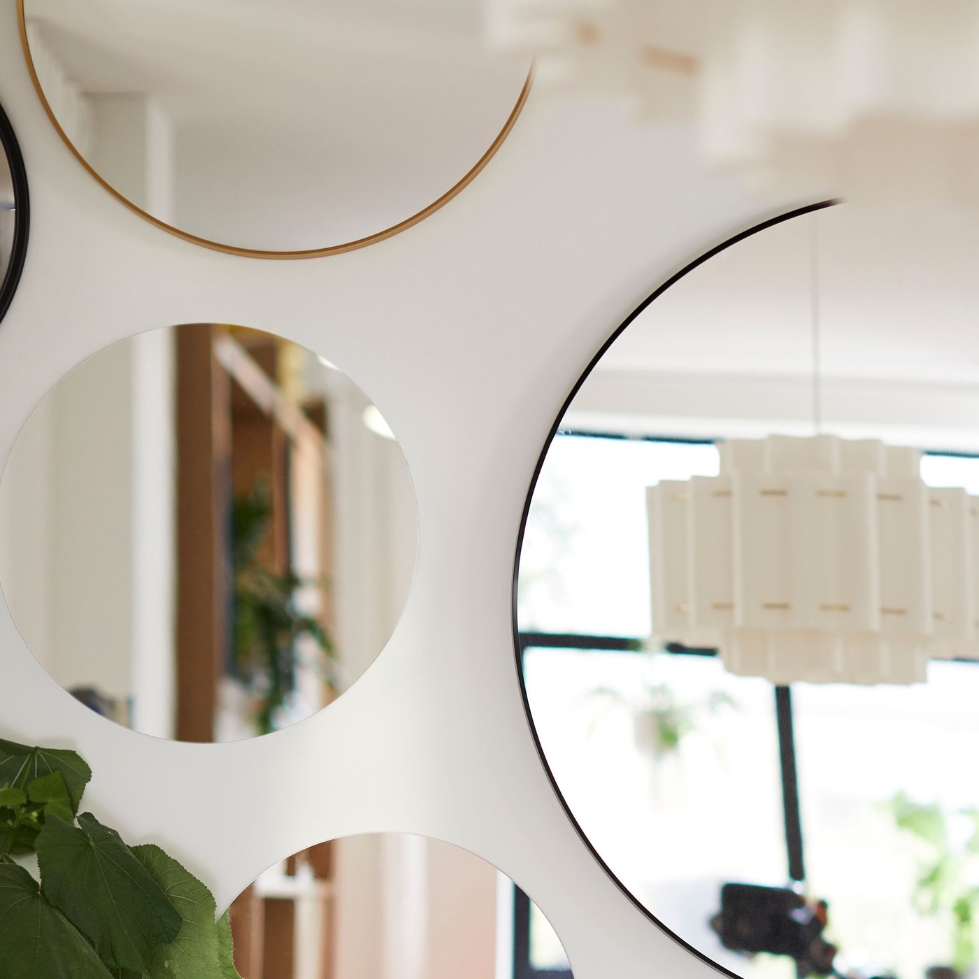 Graue FÄRGEK Dekospiegel, stilvoll an einer hellen Wand montiert. Die verschieden großen Spiegel haben ein modernes, rundes Design mit einem schmalen Rahmen in elegantem Grau.