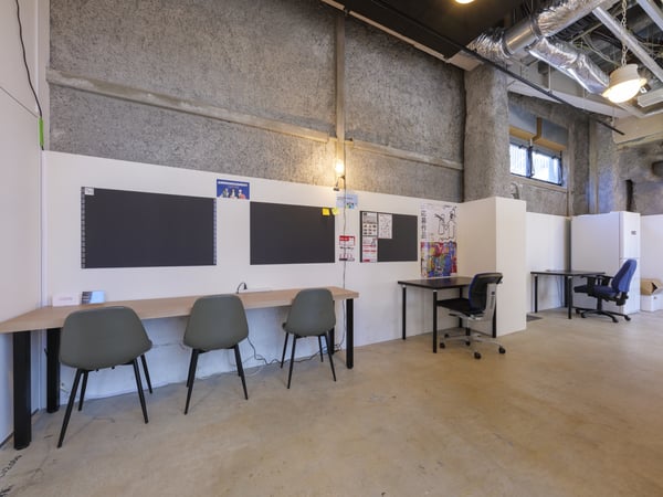 黒いペグボード付きのデスクが並ぶオフィス。仕切りで区切られた作業スペースが整然と配置されている