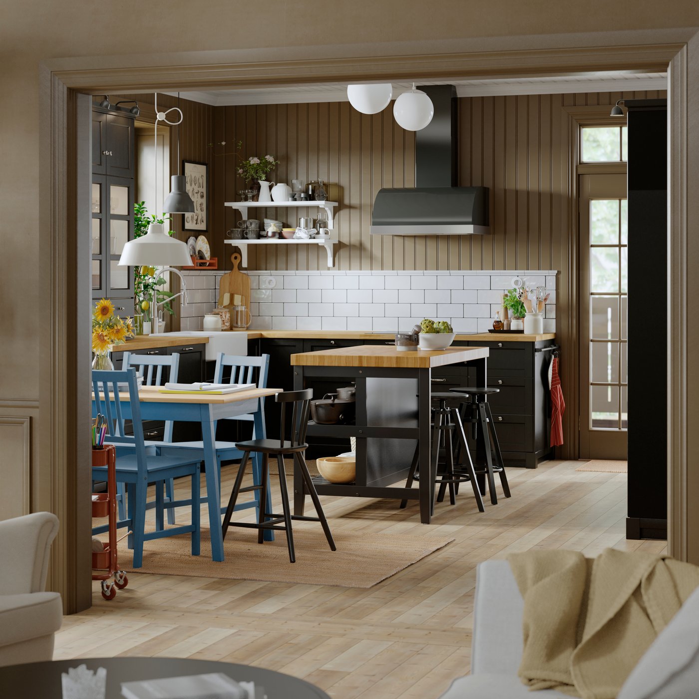 A kitchen with a black VADHOLMA kitchen island. The space is bright with wooden floors and lots of natural light.