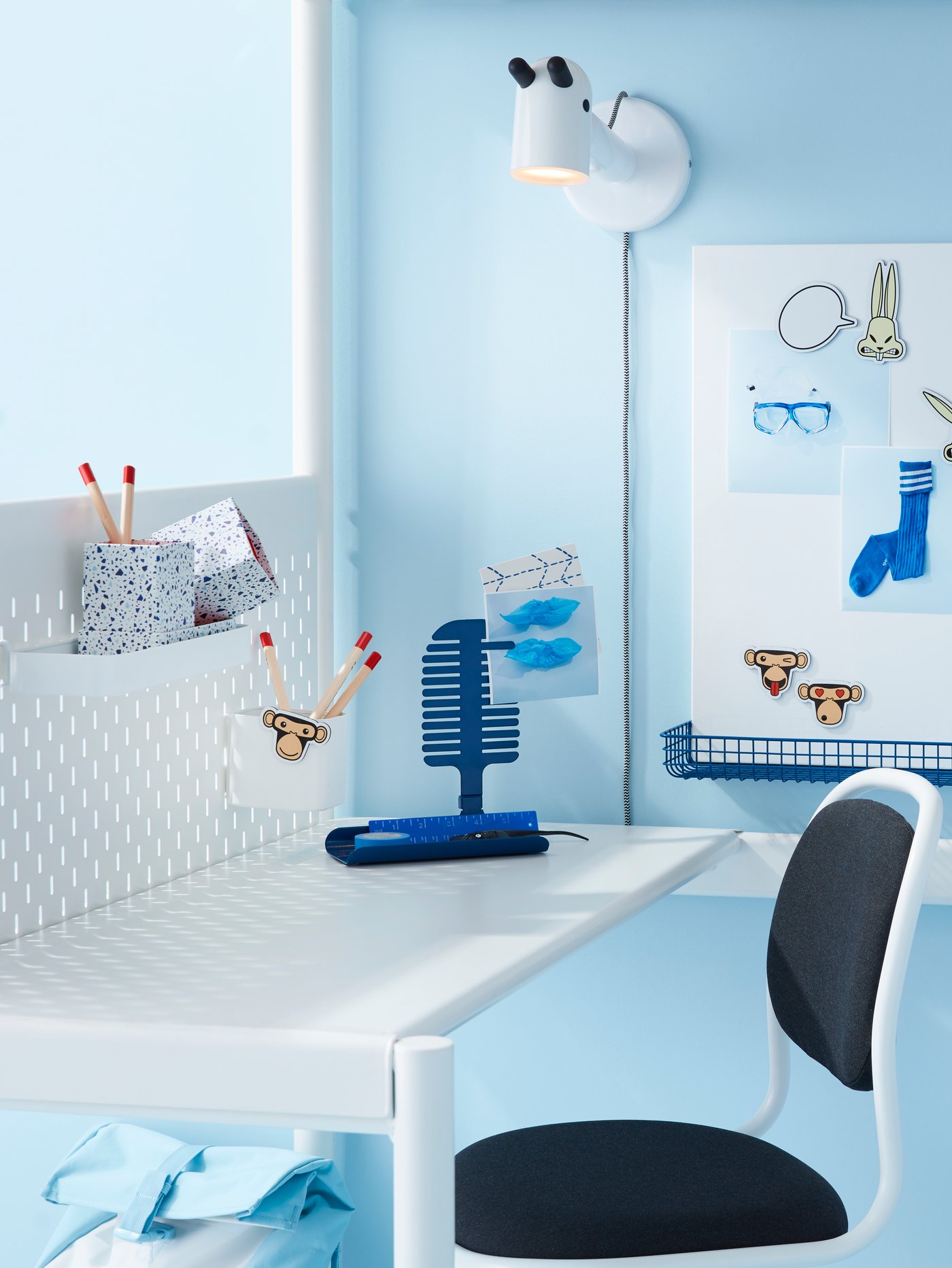 Espacio de trabajo con tablero blanco, mesa blanca, silla de escritorio para niños, lámpara de pared LED, portalápices y portafotos y utensilios de escritura.