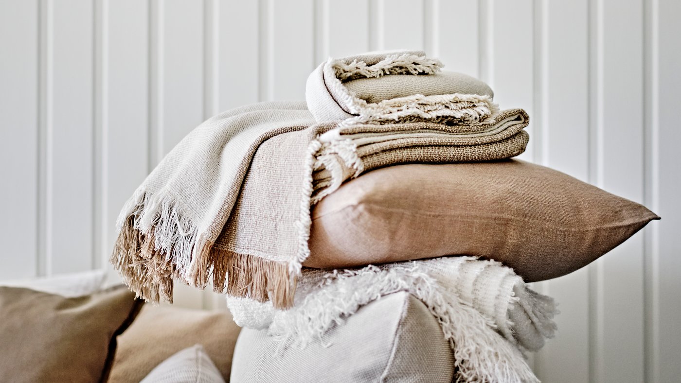 A beige AINA cushion cover