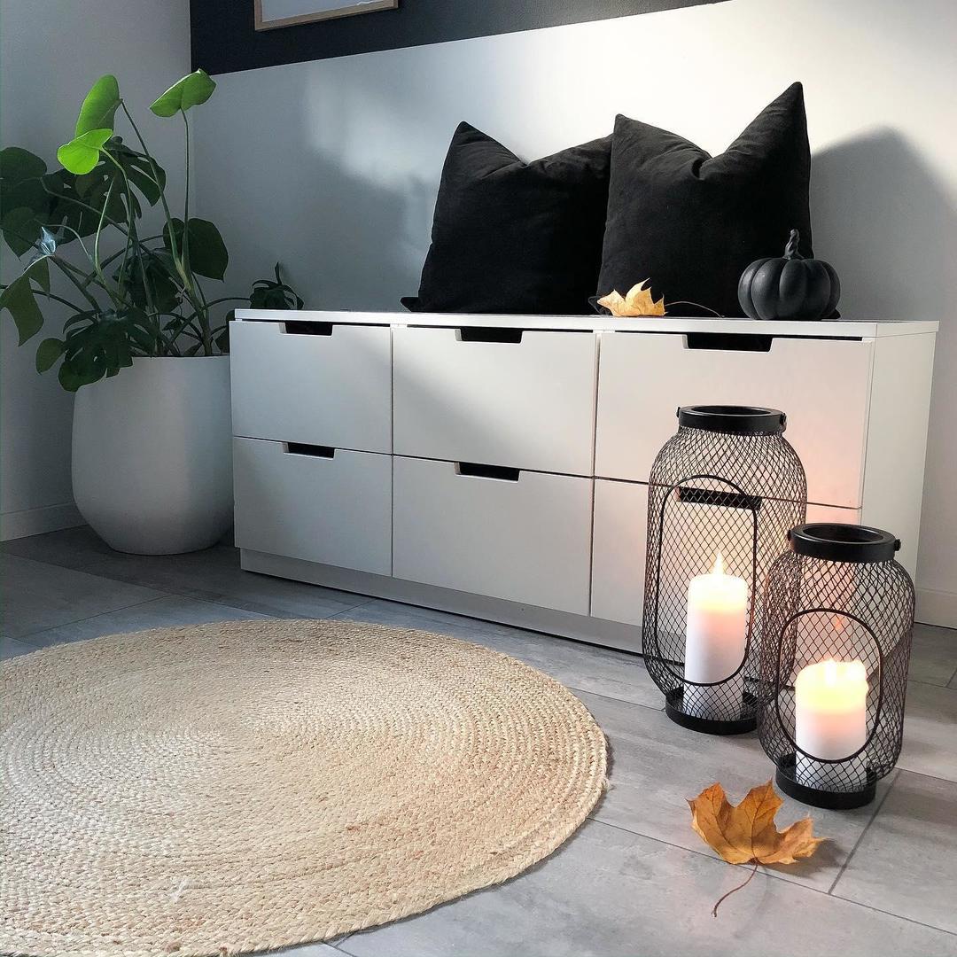 Una habitación con una cómoda NORDLI blanca de 6 cajones colocada detrás de dos farolillos TOPPIG negros para velas grandes.