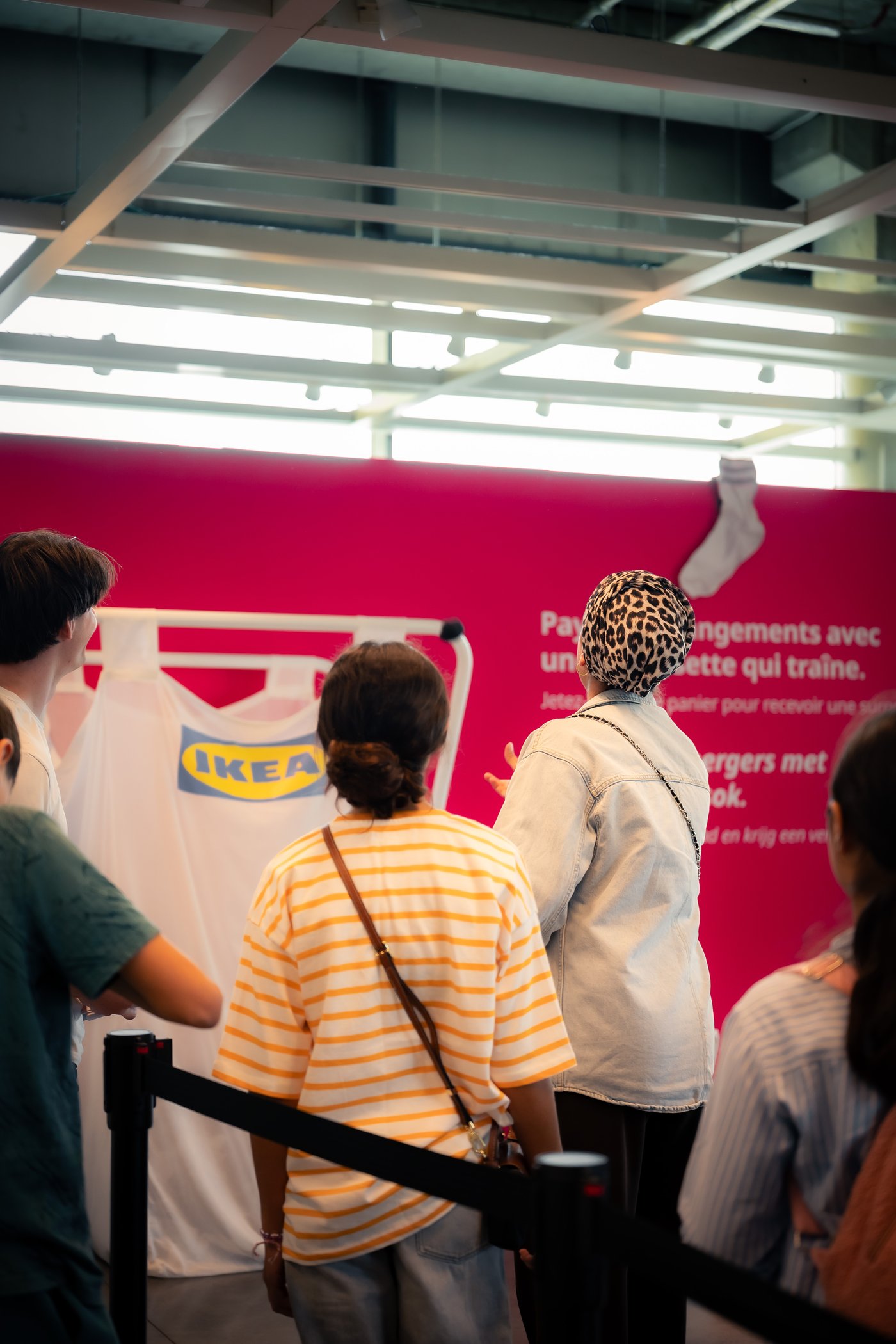 Bezoekers gooien sokken naar een IKEA-shirt tijdens een interactieve activatie in de winkel, voor een opvallende roze promotiewand.