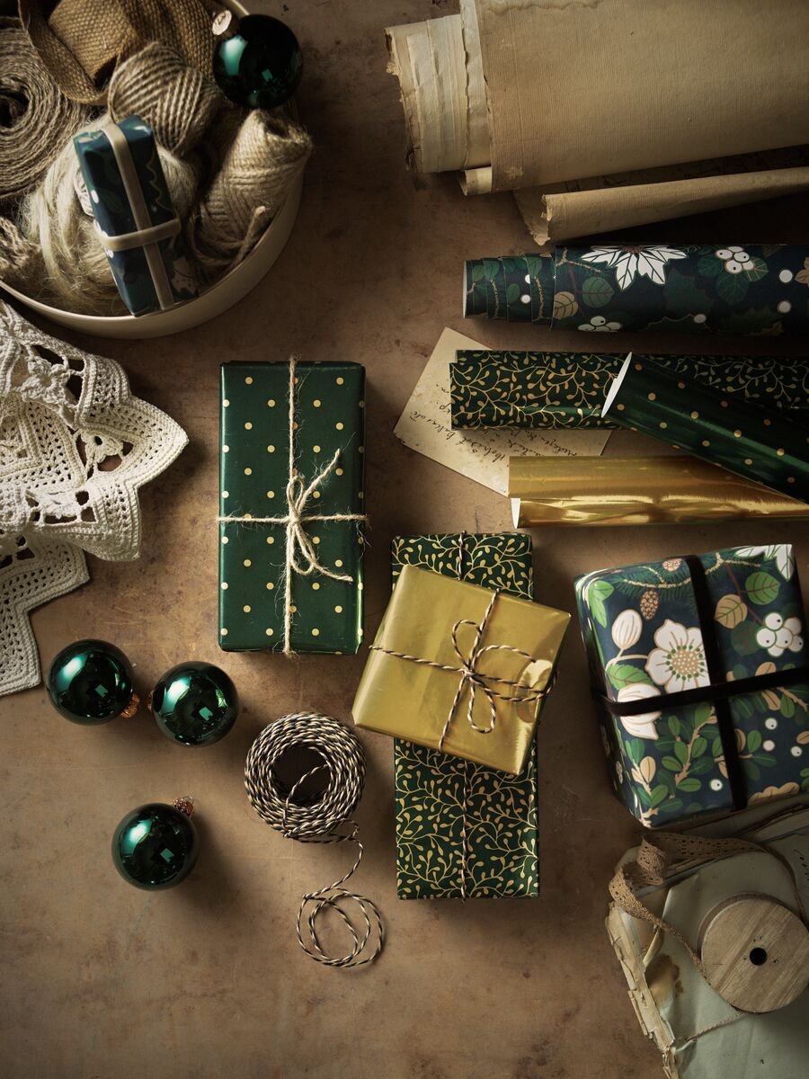 A selection of green and gold baubles, accessories and presents wrapped in VINTER 2020 paper and string.