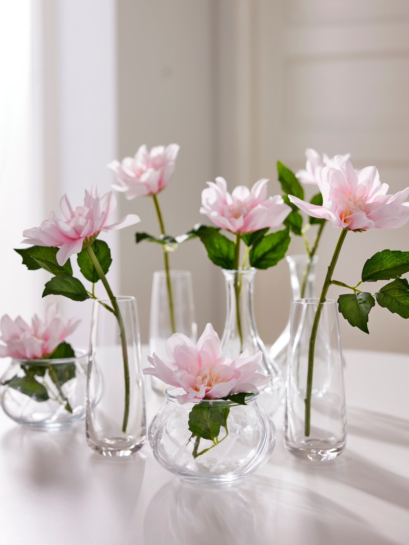 BERÄKNA vases and two sizes of VILJESTARK vases, each with one pink dahlia SMYCKA artificial flower standing in them.