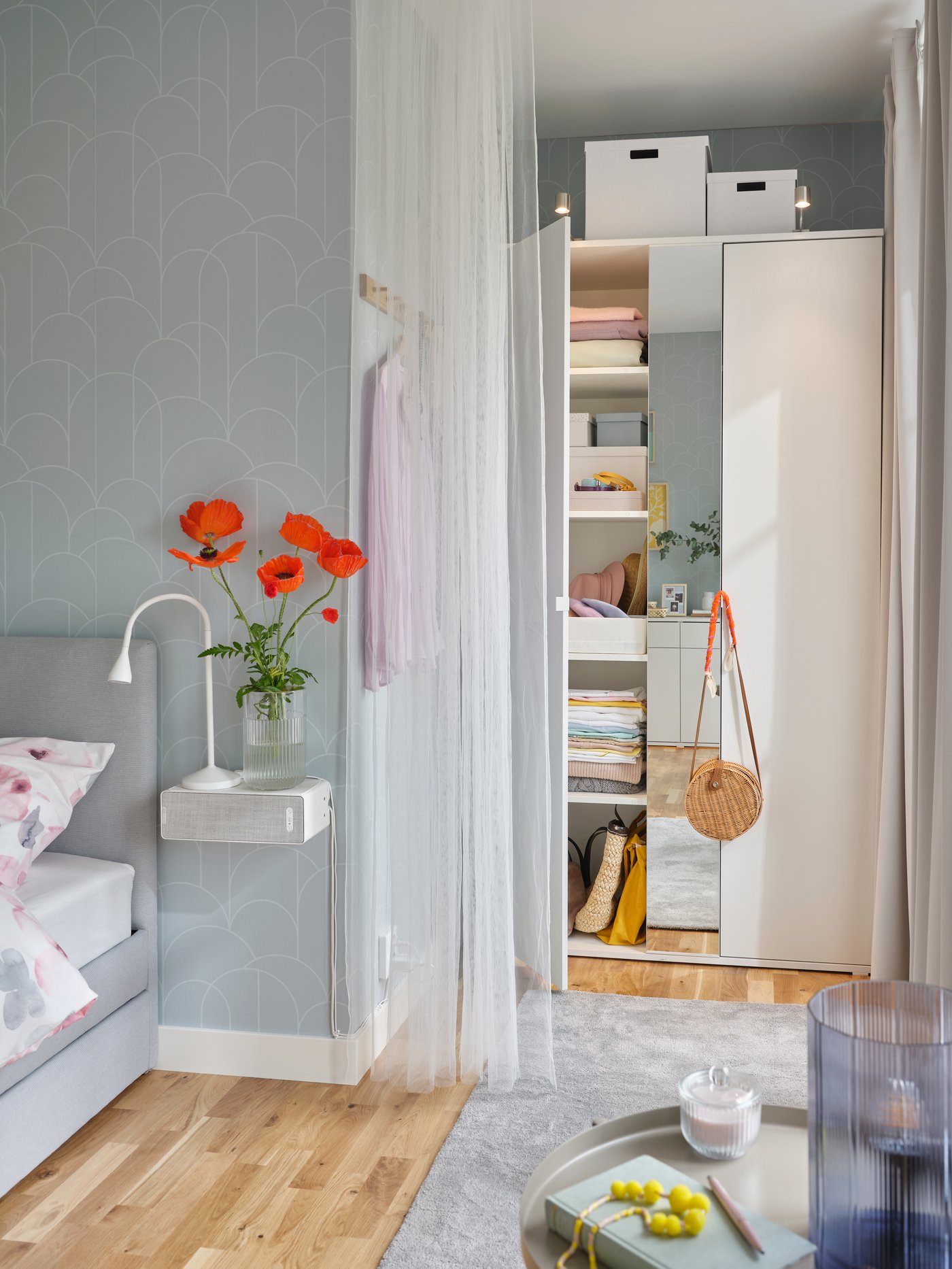 A white VIHALS wardrobe with one door open showing boxes, folded clothes and bags on the shelves inside.