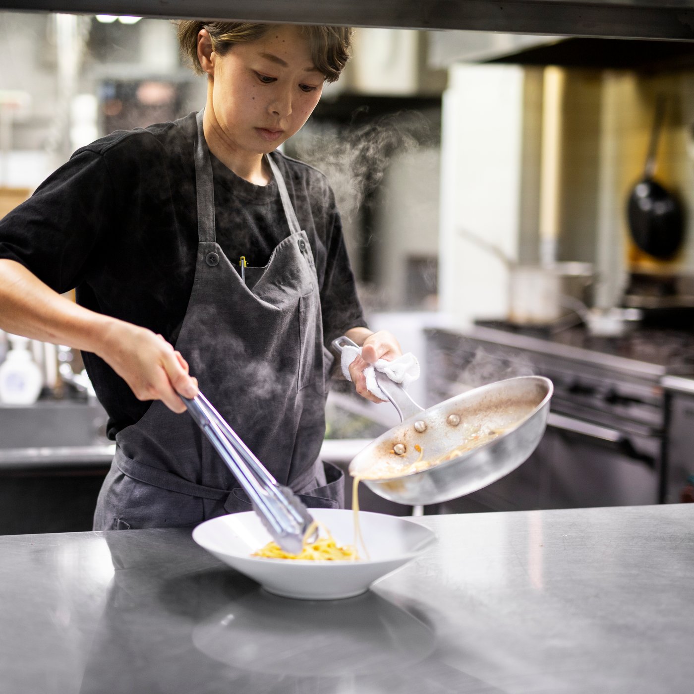 Una chef sta preparando una ricetta in una cucina inox