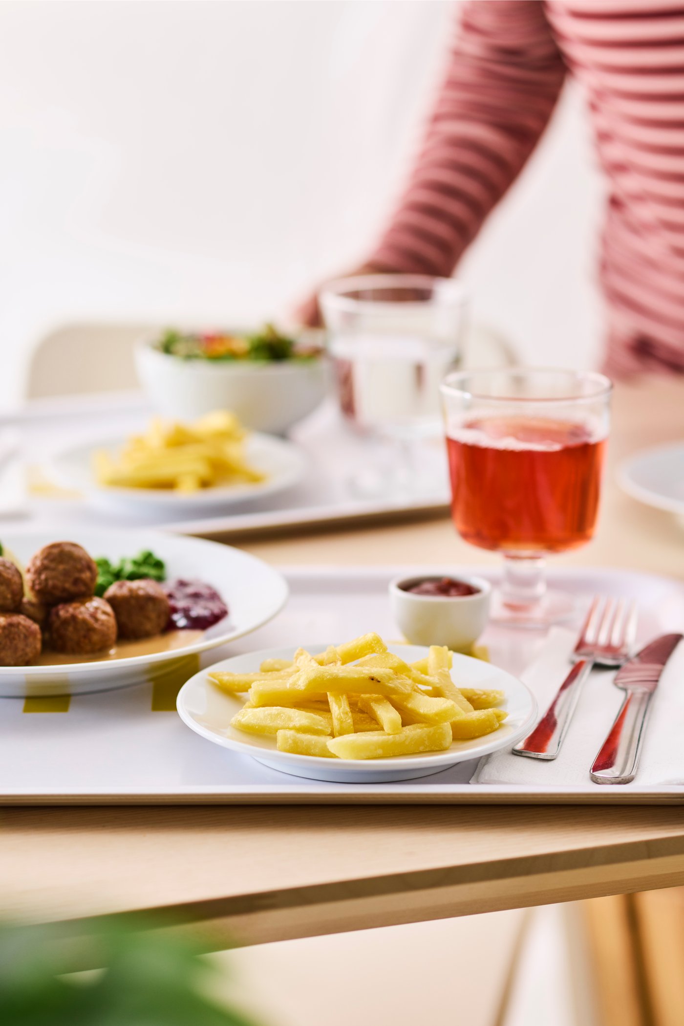 Taca z dwoma talerzami z frytkami i klopsikami, w szklance czerwony napój