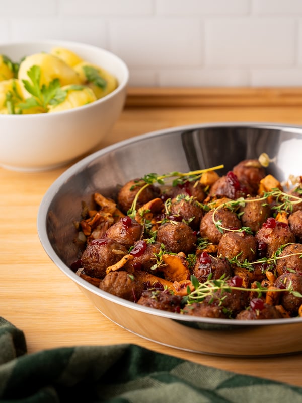 Eierschwammerln, Köttbullar & Preiselbeer-Glasur in einer Pfanne präsentiert.