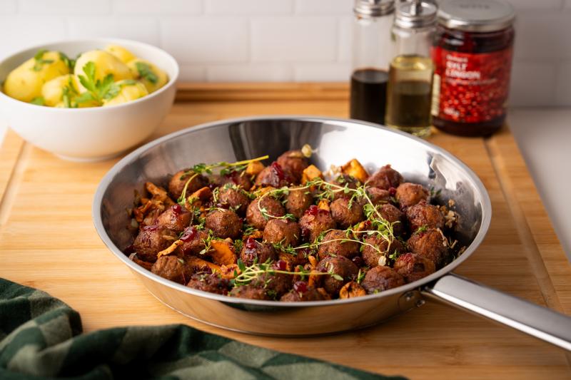 Eierschwammerln, Köttbullar & Preiselbeer-Glasur in einer Pfanne präsentiert.