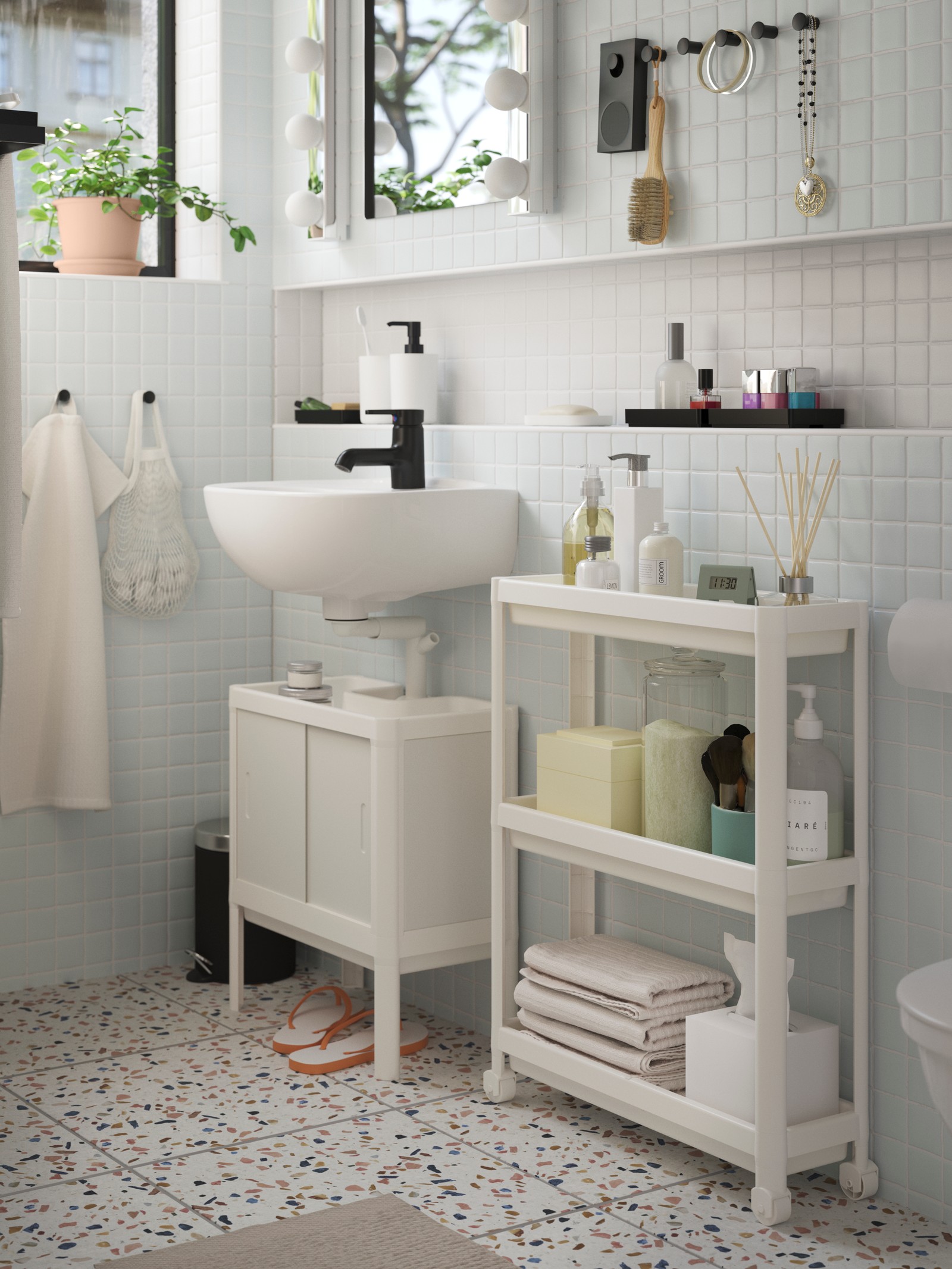 Un baño con muebles blancos y negros que combina un vanitorio ENHET y estantes abiertos. Sobre el lavamanos un botiquín con espejos de puertas corredizas.