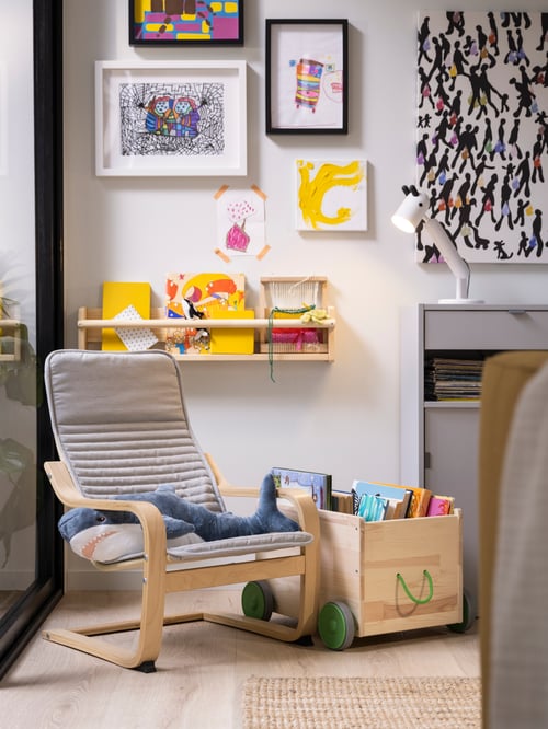 In a children's room there is a FLISAT toy storage with wheels, a wall storage, and multiple pictures on the wall.
