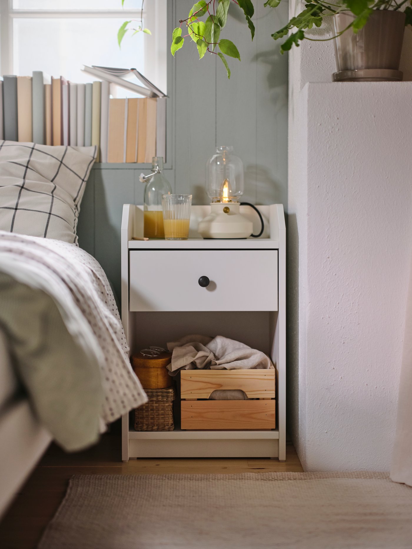 Biała szafka nocna HAUGA stojąca przy łóżku.