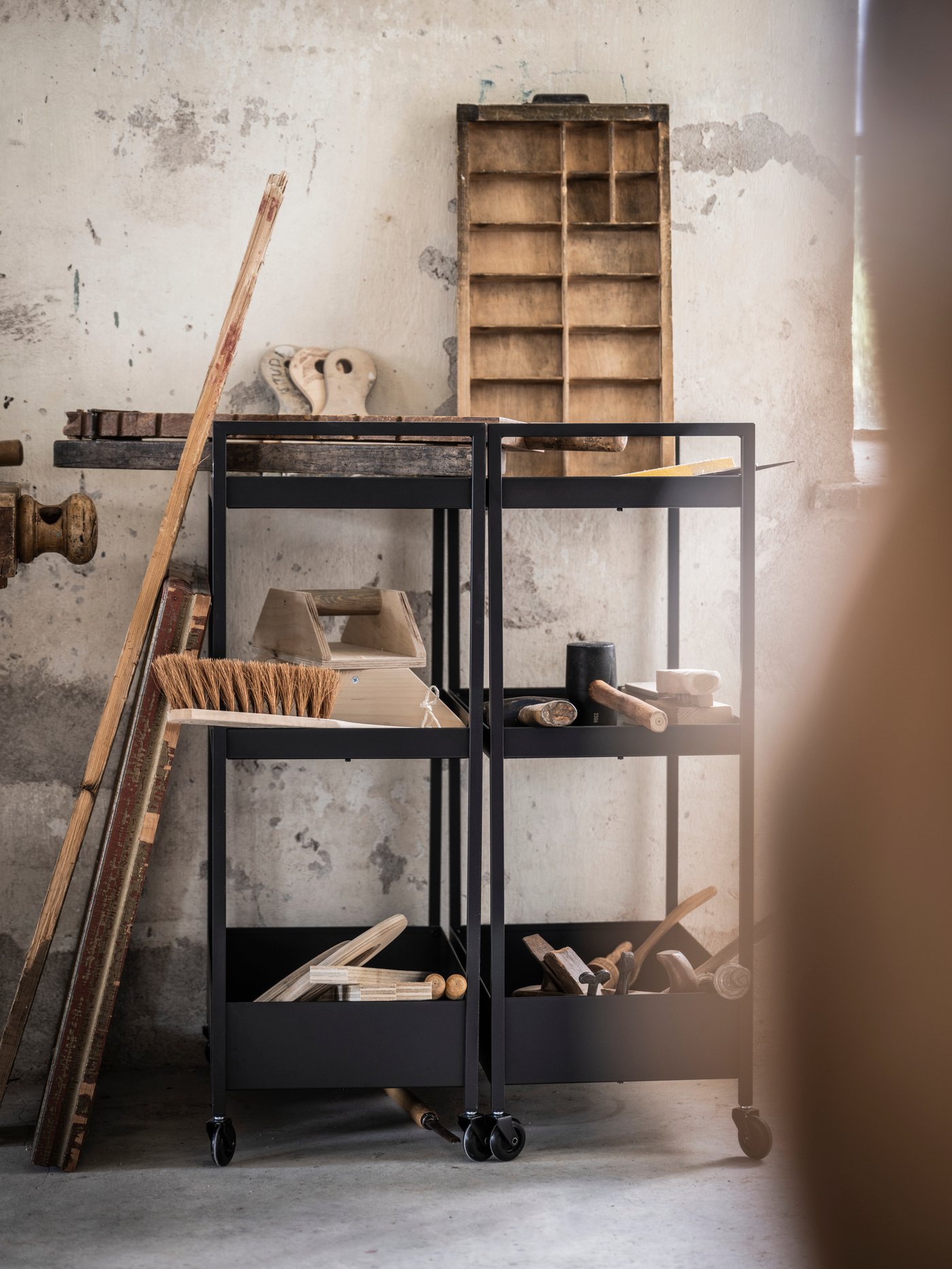 Dans un garage, une desserte NISSAFORS noire servant de rangement pour outils et objets d'entretien de nettoyage.