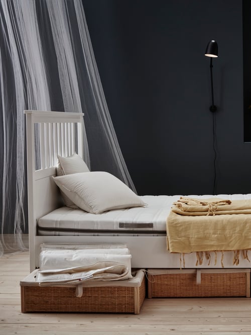 Bedroom with black wall, white wooden bed frame, foam mattress, firm pillows, wall lamp, bed storage boxes, net curtains.