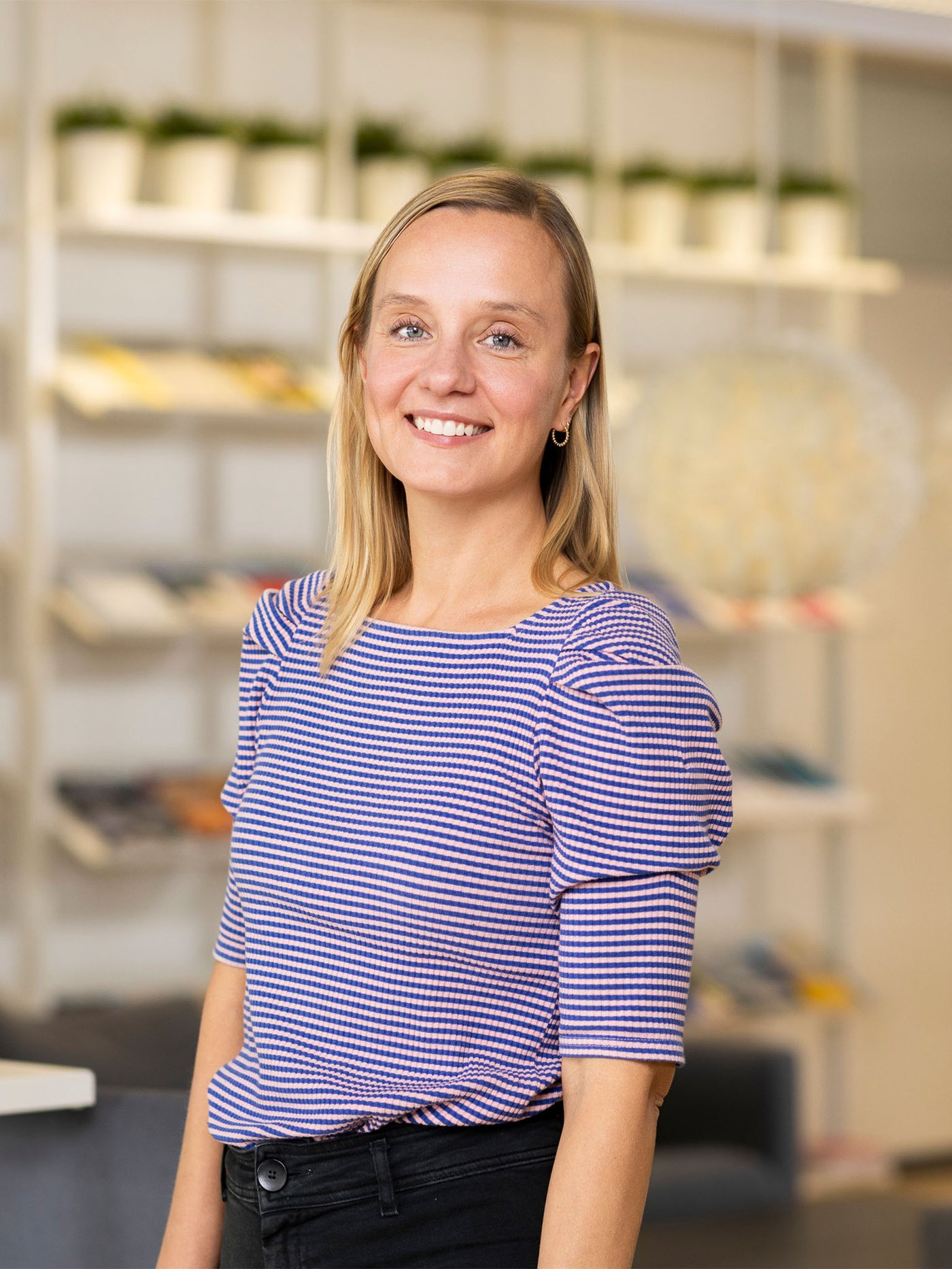 照明や家具が並ぶショールームで、ボーダートップスを着たイケアのコワーカーが通路に立っている