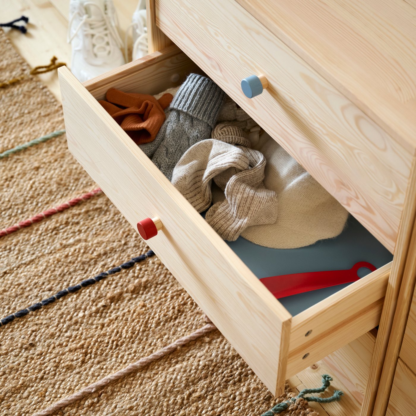 Close-up of one drawer of RAST chests of drawers pulled out to show socks and things inside. RAKLEV rug on floor below.