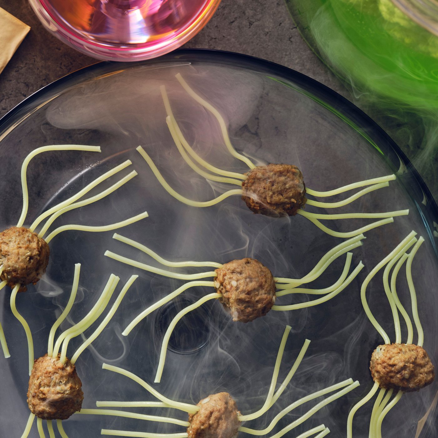 Spider meatballs made with HUVUDROLL plant balls or meatballs and spaghetti for legs on a black plate with smoke.