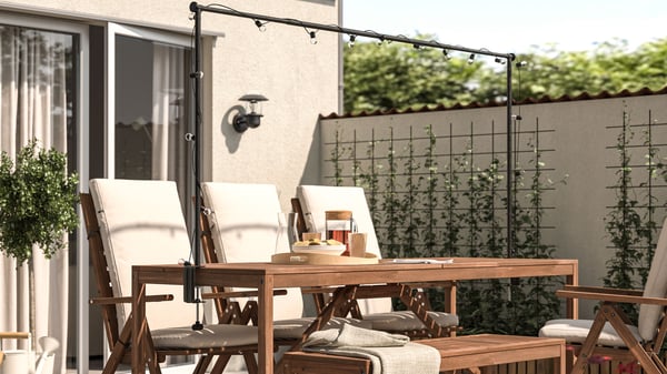 An outdoor light brown stained/black HELGEÖ table with decorating rod