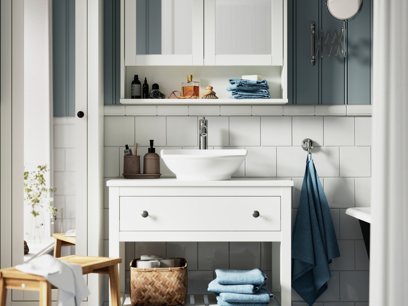 A bright bathroom has a HEMNES wash-stand with a white VÄSTERSJÖN countertop washbasin and a white mirror cabinet above it.