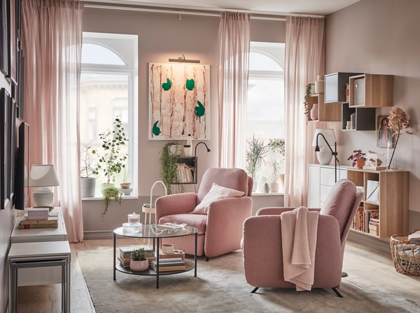 Ett vardagsrum med två EKOLSUND vilfåtöljer med ljust brunrosa GUNNARED klädsel som står framför fönster som släpper in dagsljus.