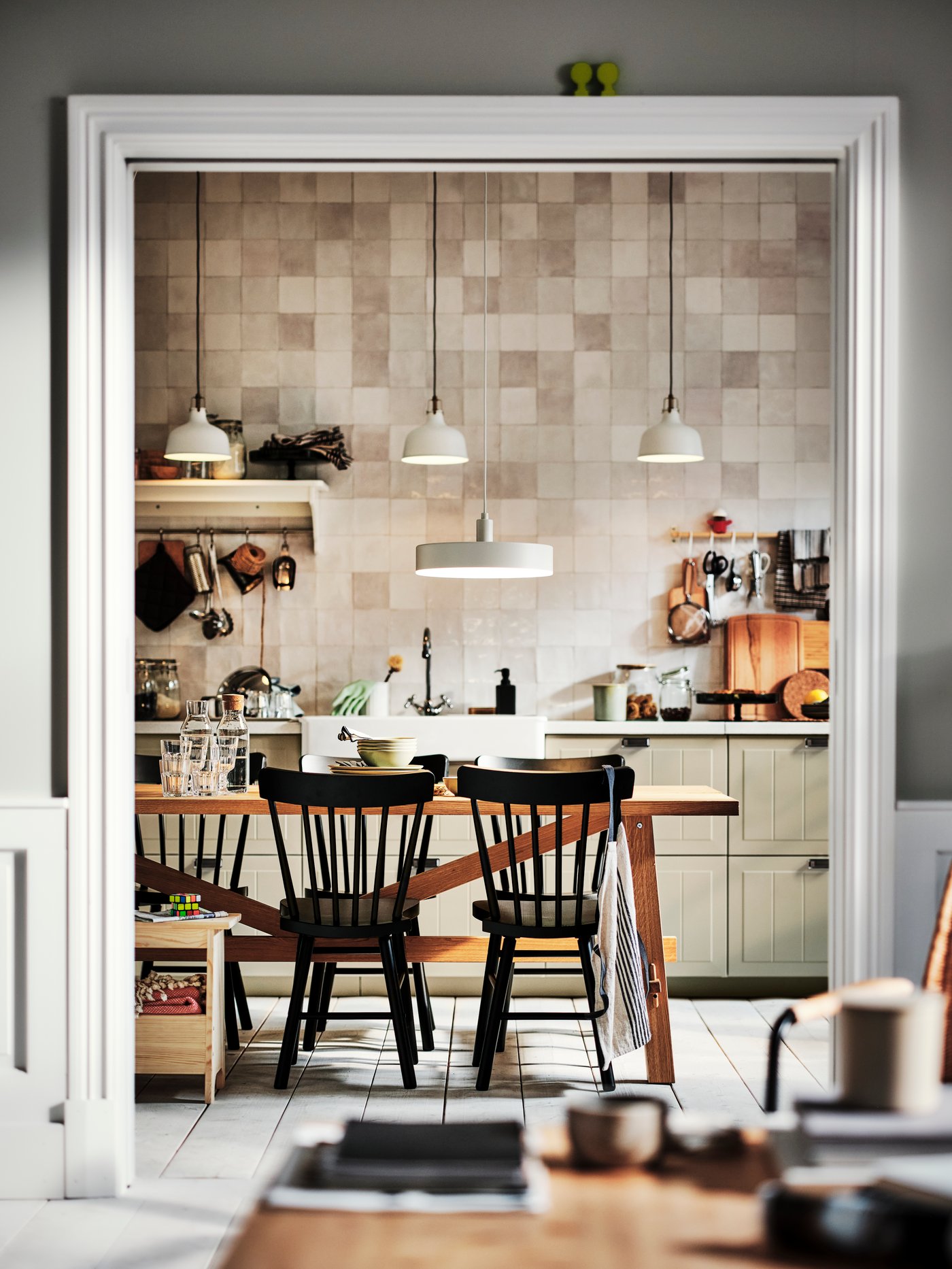 A kitchen with beige STENSUND drawer fronts and an oak MÖCKELBY table surrounded by black NORRARYD chairs.