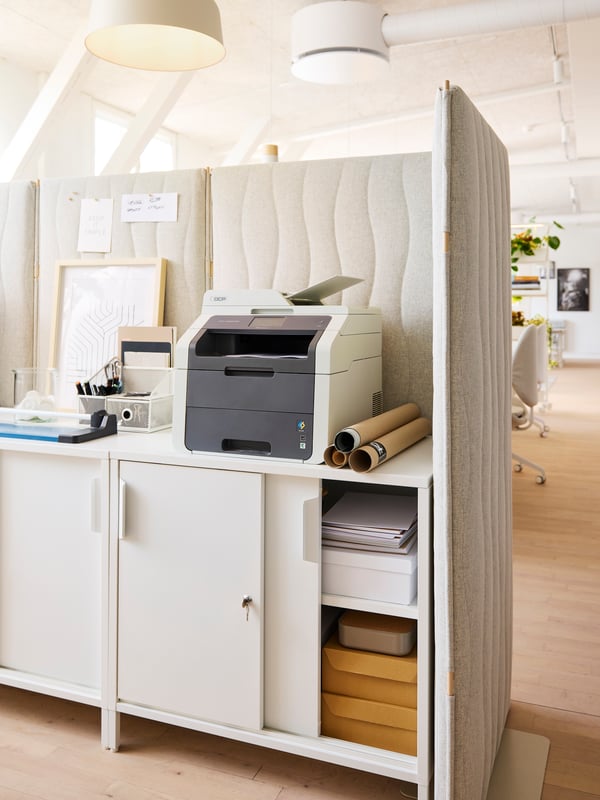 A Gunnared beige MITTZON acoustic screen holding different office accessories sits in an office setting.