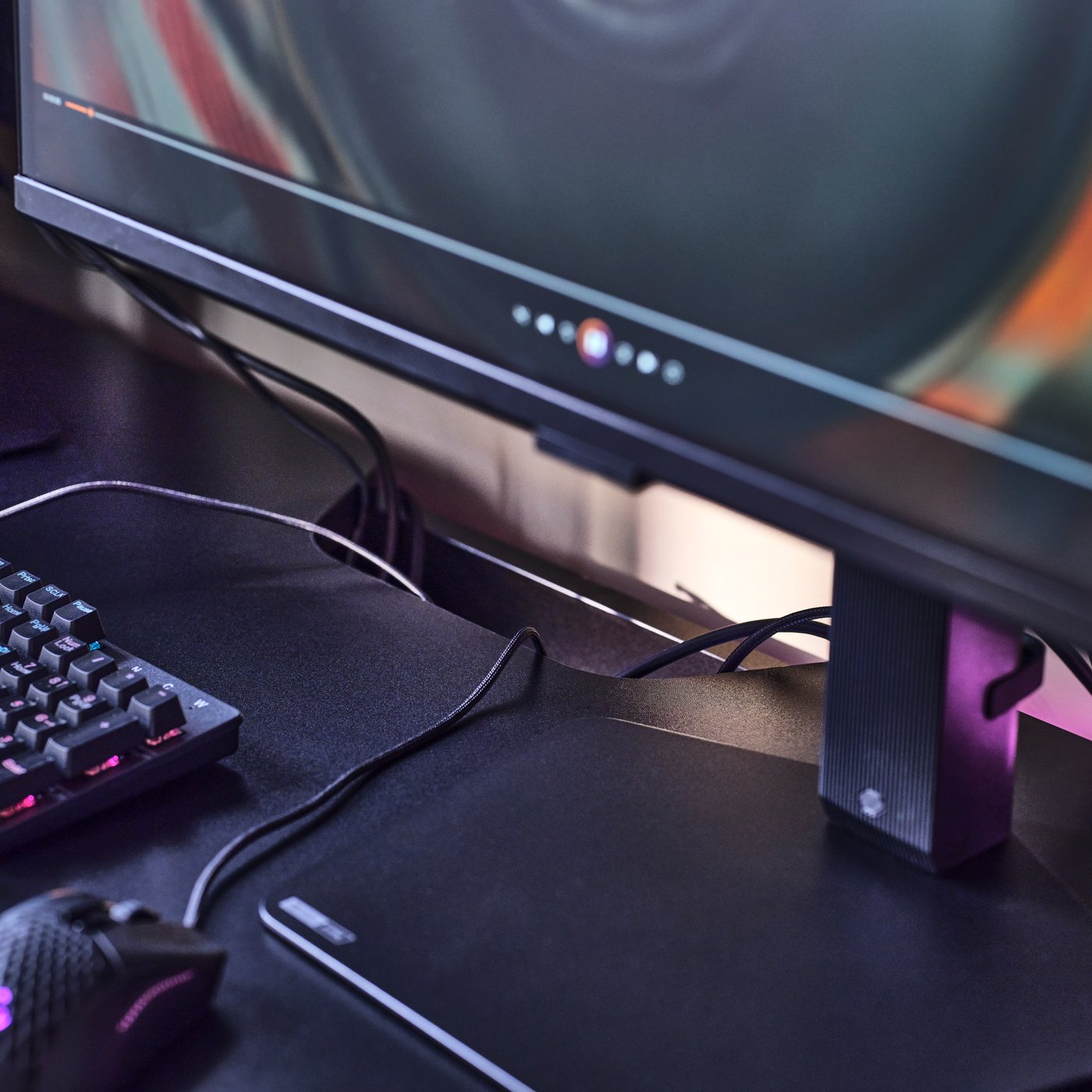 Detalles de una estación de juego sobre un escritorio gamer FRÖSKELÅS, donde los cables del monitor, mouse y teclado desaparecen en una abertura integrada en el tablero.