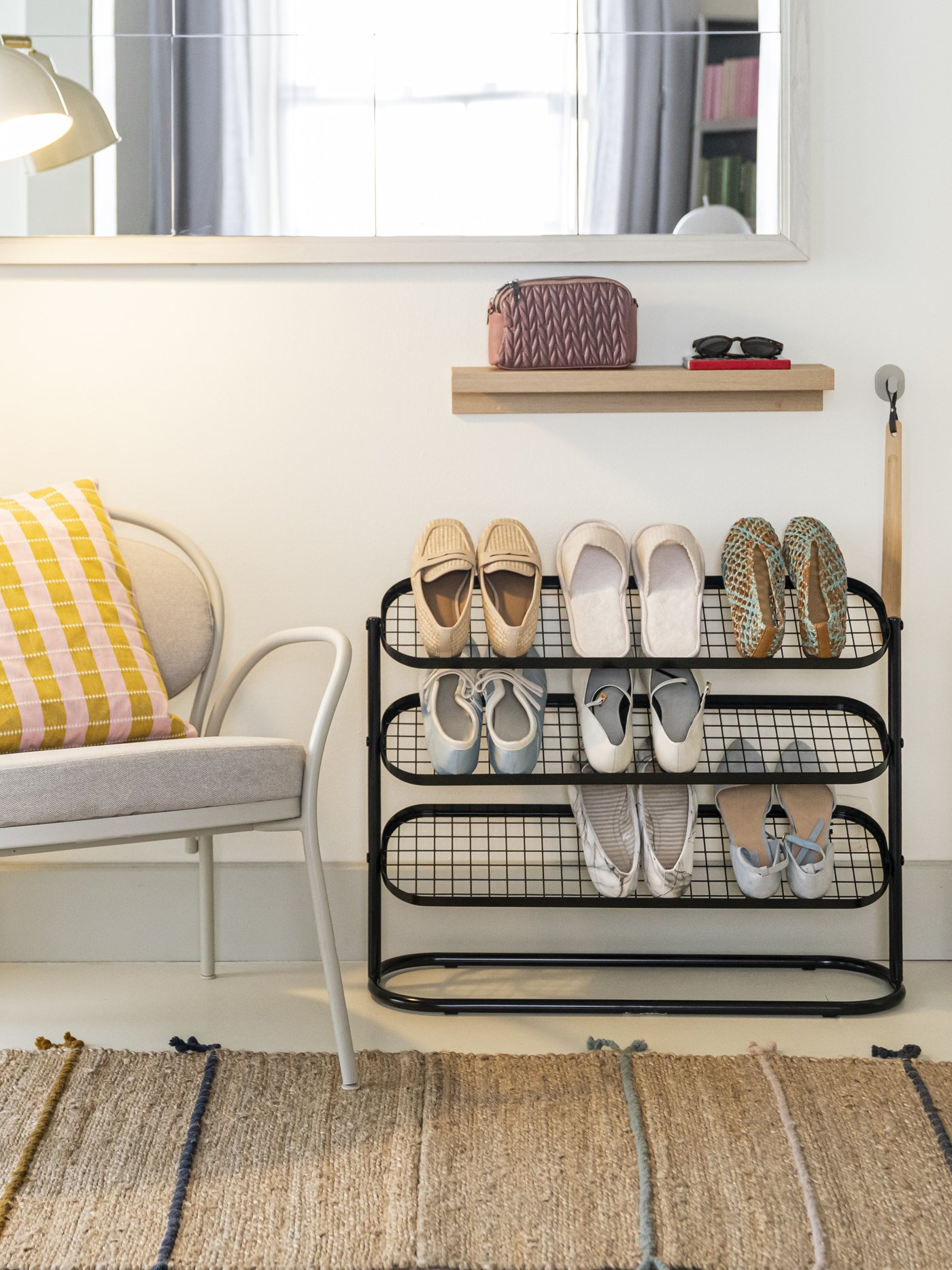 Calzascarpe HÖSVANS in bambù appeso alla parete accanto a una scarpiera ÄLGANÄS nera, in un ingresso arredato.