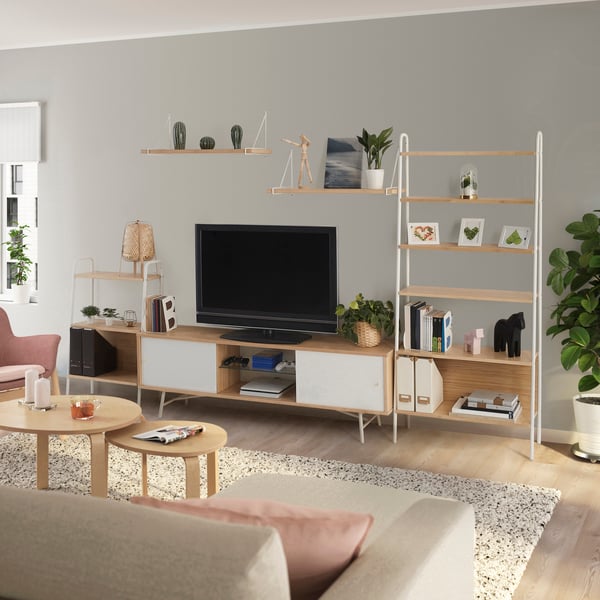 Een studentenkamer met een tv-meubel, een beige bank en een vloerkleed met daarop houten salontafels.