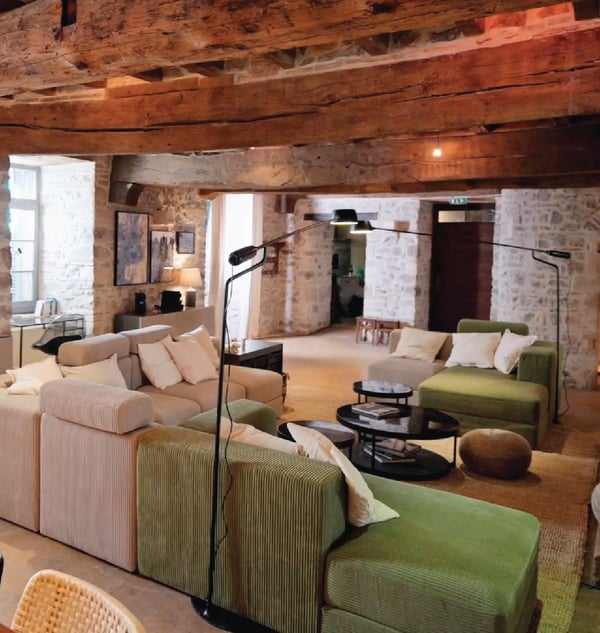 Canapés beige et vert en velour avec des lampadaires et table basse ronde.