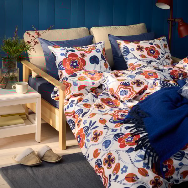 A KANONVISKA duvet cover set featuring a white multicolour floral pattern, styled with matching pillows on a cosy bed.