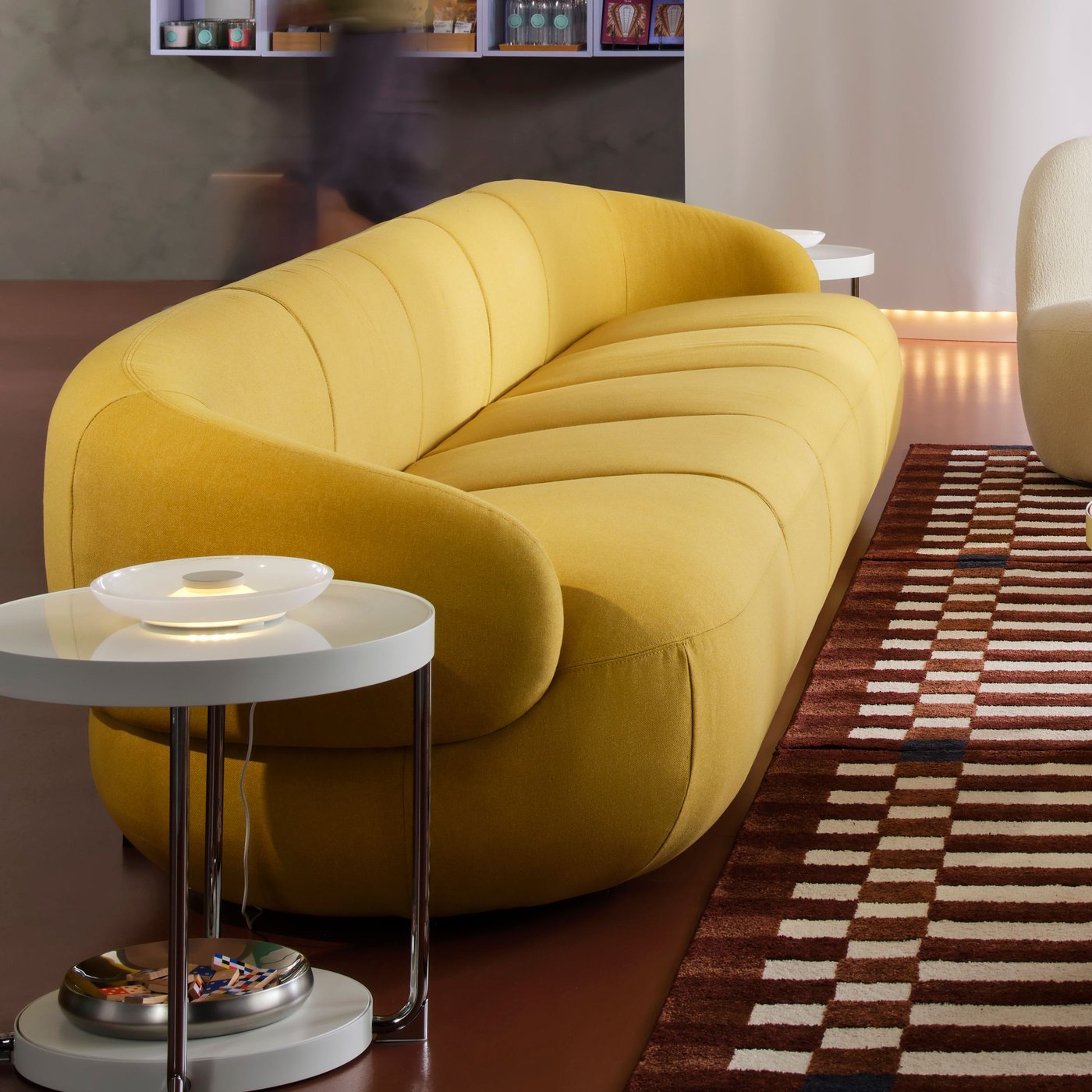 A bright green-yellow LILLESÄTER 6-seat sofa stands at the edge of some multicoloured rugs in a large room.