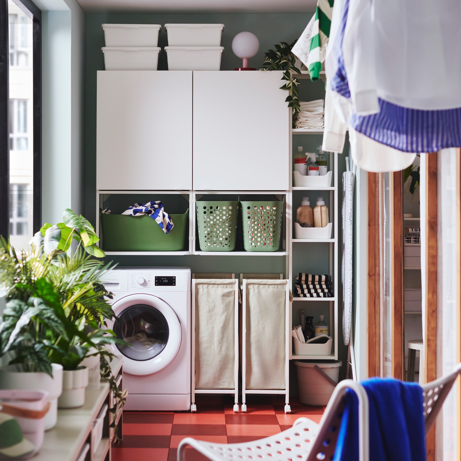 A white ENHET storage combination with wall shelves and cabinets is above a washing machine in a modern balcony laundry area.