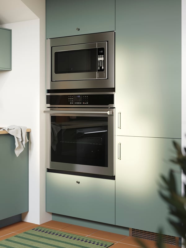 A kitchen with NICKEBO fronts in matt grey-green with integrated fridge/freezer, a built-in oven and microwave oven.