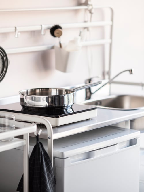 Modern kitchen with a white mini kitchen with reversible shelf and adjustable feet, supporting a portable induction hob.